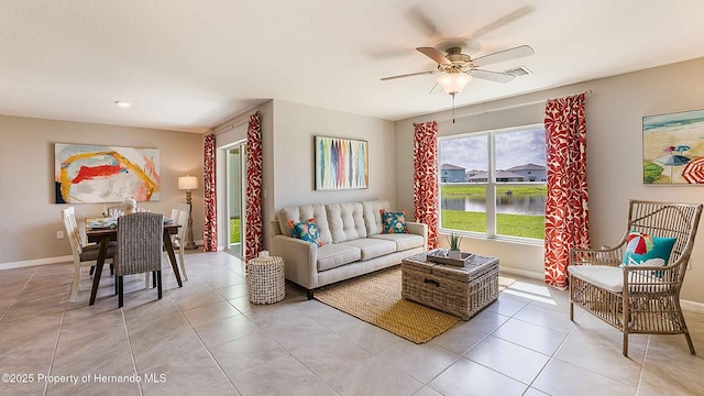 tiled living room with ceiling fan and a water view