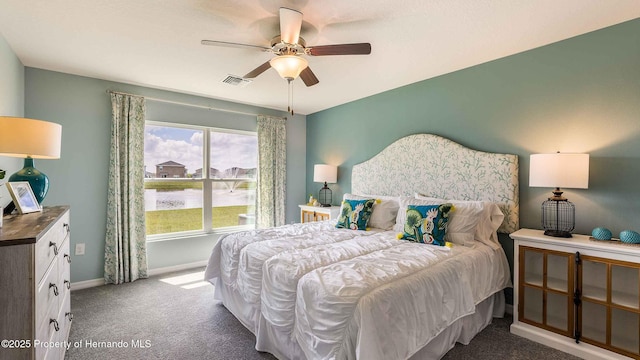 carpeted bedroom featuring multiple windows, ceiling fan, and a water view