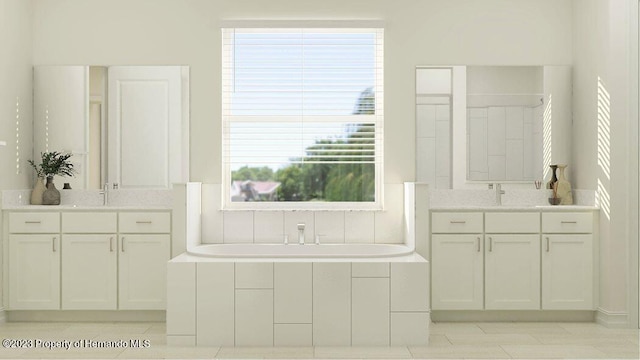 bathroom with tile patterned flooring, vanity, and tiled bath