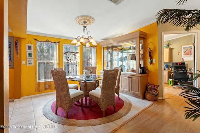 tiled dining room with ornamental molding and a notable chandelier