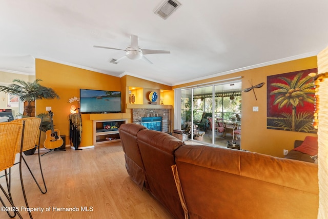 living room with light hardwood / wood-style flooring, a fireplace, ornamental molding, and ceiling fan