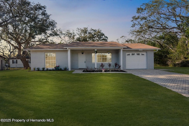 ranch-style home featuring a lawn, covered porch, and a garage