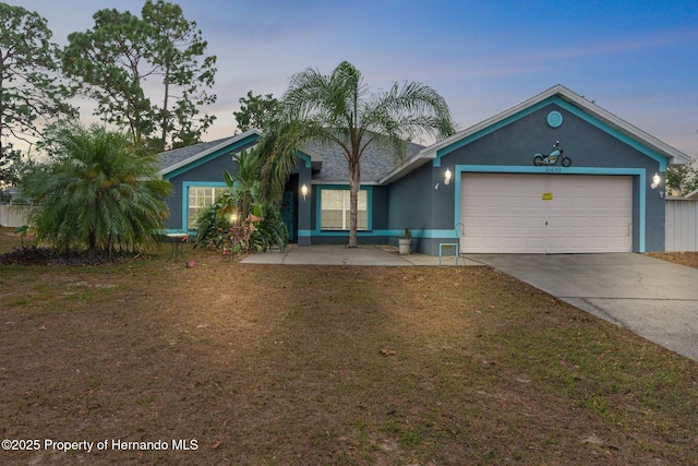 ranch-style house with a front lawn, an attached garage, concrete driveway, and stucco siding