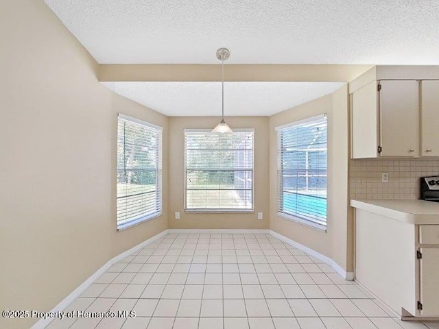 unfurnished dining area with light tile patterned floors, a textured ceiling, and a healthy amount of sunlight