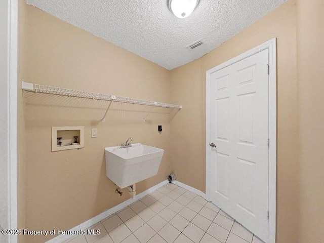 washroom featuring sink, light tile patterned floors, washer hookup, and a textured ceiling