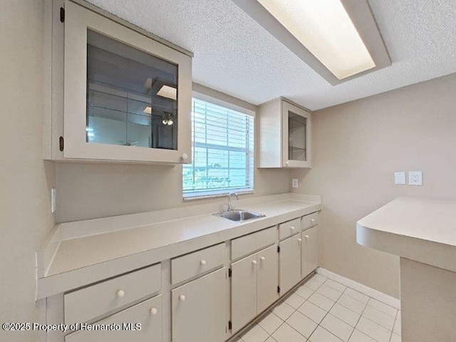 kitchen featuring sink, white cabinets, and a textured ceiling