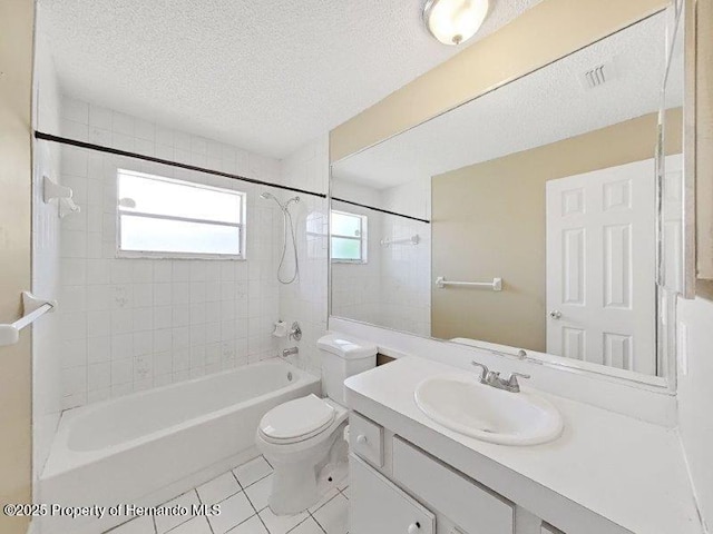 full bathroom with vanity, tile patterned floors, tiled shower / bath, toilet, and a textured ceiling