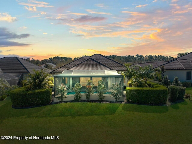 back house at dusk with a lawn