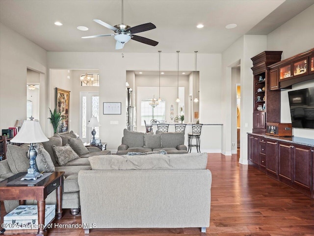 living room with dark hardwood / wood-style flooring and ceiling fan with notable chandelier