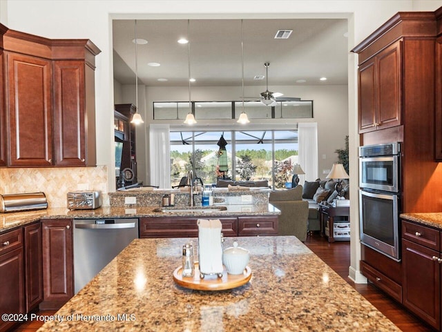 kitchen with sink, hanging light fixtures, tasteful backsplash, light stone counters, and stainless steel appliances