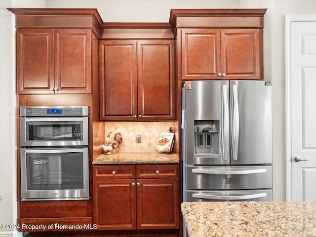 kitchen with backsplash, light stone countertops, and stainless steel appliances