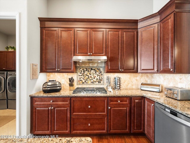 kitchen with tasteful backsplash, light stone countertops, washer and clothes dryer, and stainless steel appliances