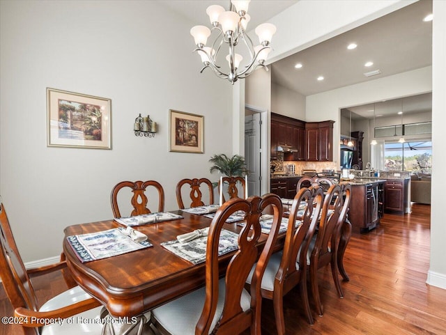 dining area with sink, light hardwood / wood-style floors, and a notable chandelier