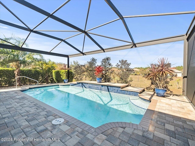 view of pool featuring glass enclosure and a patio