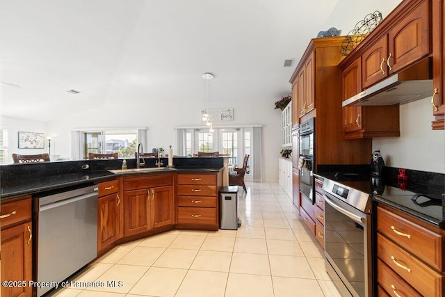 kitchen featuring lofted ceiling, sink, dark stone countertops, light tile patterned floors, and stainless steel appliances