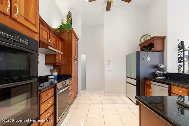 kitchen with stainless steel appliances, ceiling fan, dark stone countertops, and light tile patterned flooring