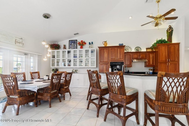 kitchen with hanging light fixtures, oven, lofted ceiling, a breakfast bar, and light tile patterned flooring