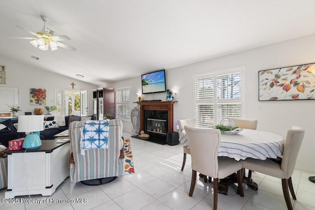 tiled dining room featuring vaulted ceiling, ceiling fan, and a premium fireplace