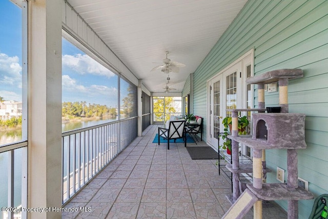 sunroom / solarium with ceiling fan and a water view