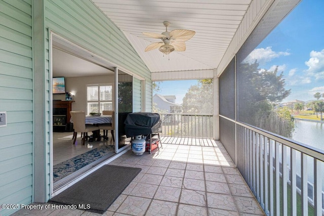 sunroom / solarium with ceiling fan, a water view, and vaulted ceiling