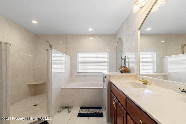 bathroom with plus walk in shower, vanity, tile patterned floors, and a wealth of natural light