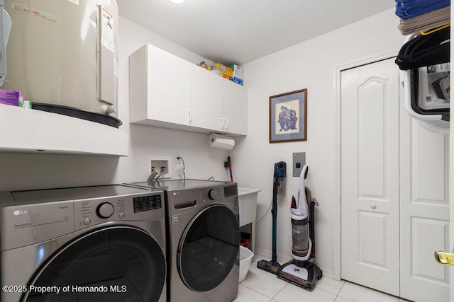 clothes washing area with cabinets, light tile patterned floors, a textured ceiling, and washer and dryer