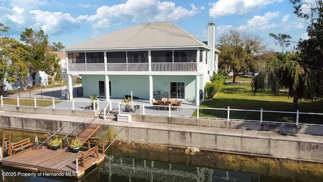 back of property with a patio area, a sunroom, a yard, and a water view