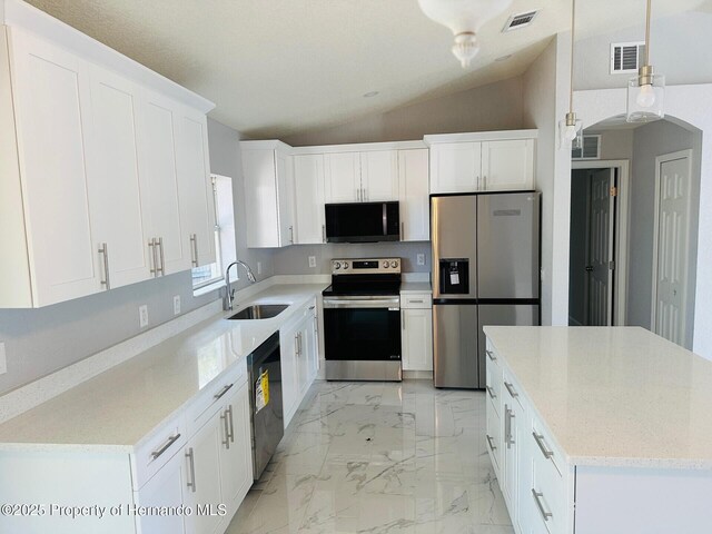 kitchen with lofted ceiling, sink, light stone countertops, appliances with stainless steel finishes, and white cabinetry