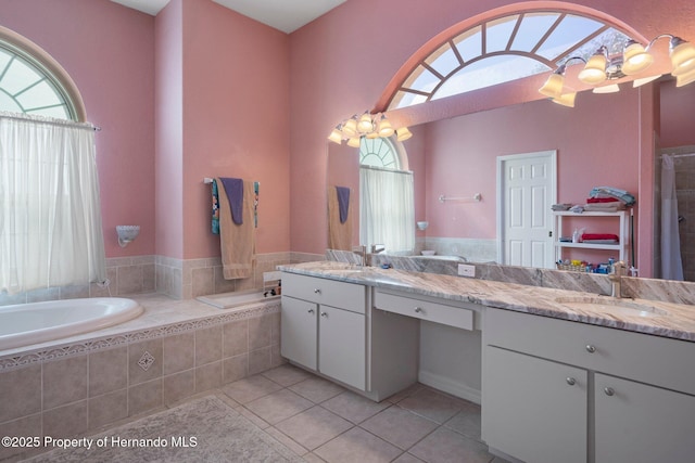 bathroom featuring a relaxing tiled tub, tile patterned flooring, and vanity