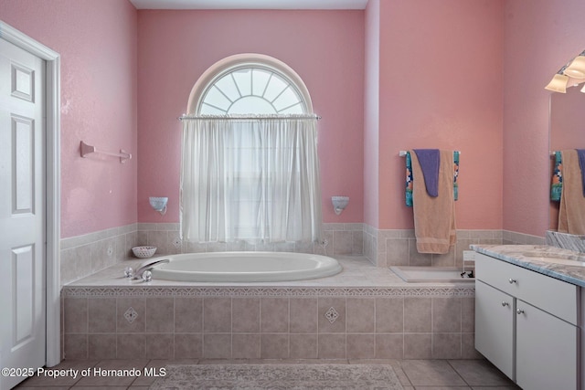 bathroom featuring vanity, tile patterned flooring, and a relaxing tiled tub