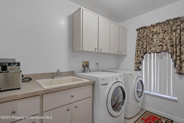 clothes washing area with sink, washing machine and clothes dryer, light tile patterned floors, and cabinets