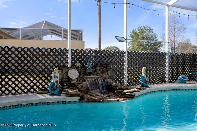 view of swimming pool featuring a lanai