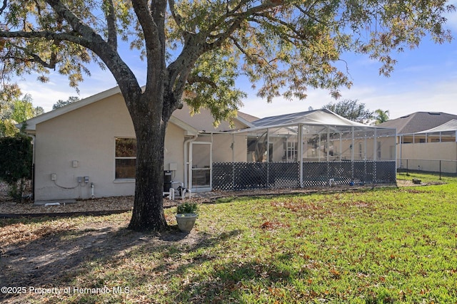 rear view of property with a lawn and a lanai