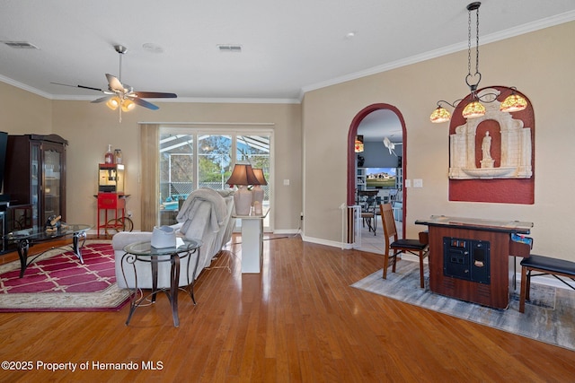 living room with wood-type flooring, ceiling fan, and crown molding