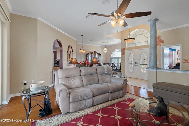 living room featuring ornamental molding, light wood-type flooring, ceiling fan, and french doors