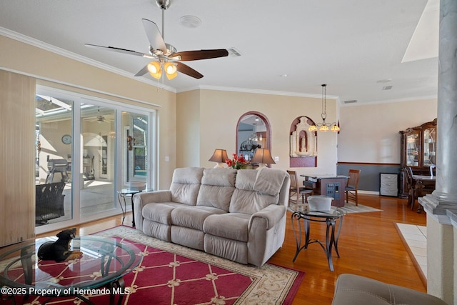 living room featuring ornate columns, ceiling fan with notable chandelier, hardwood / wood-style flooring, and crown molding