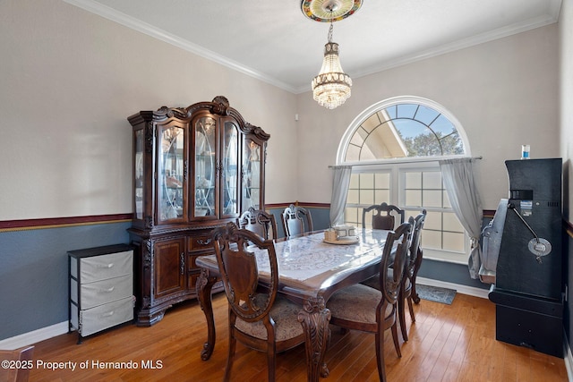 dining space with a notable chandelier, crown molding, and wood-type flooring