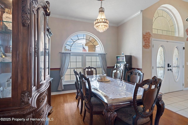 dining room with light wood-type flooring, an inviting chandelier, french doors, and a healthy amount of sunlight