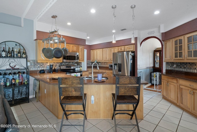 kitchen featuring stainless steel appliances, kitchen peninsula, a breakfast bar, sink, and backsplash