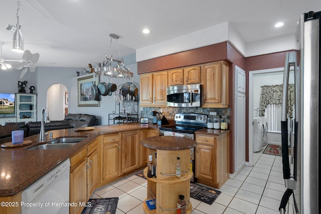 kitchen featuring sink, stainless steel appliances, a kitchen island, and pendant lighting