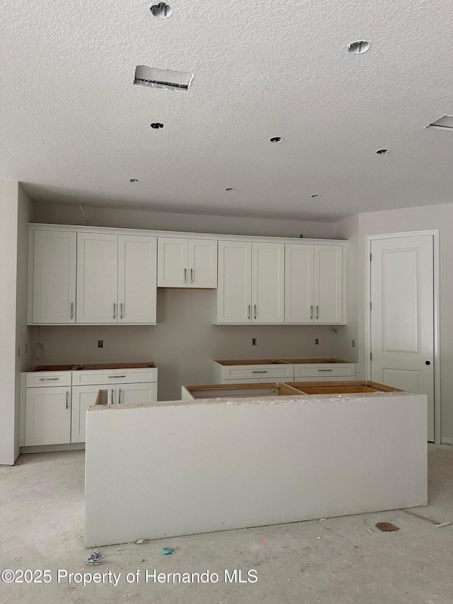 kitchen featuring a textured ceiling, white cabinetry, and a kitchen island