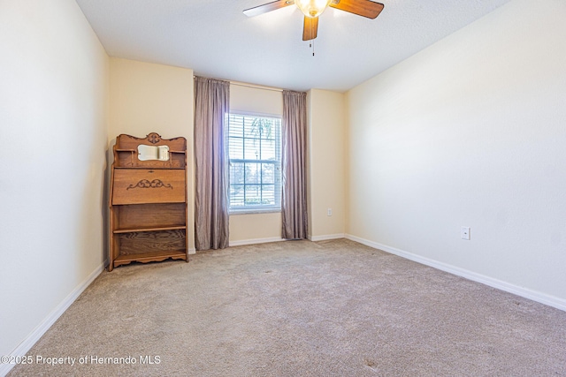 spare room featuring ceiling fan, baseboards, and carpet