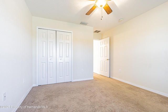 unfurnished bedroom featuring baseboards, light carpet, a closet, and visible vents