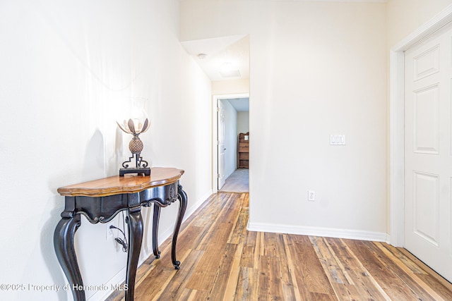 hallway featuring baseboards and wood-type flooring