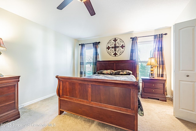 bedroom featuring light colored carpet, a ceiling fan, and baseboards