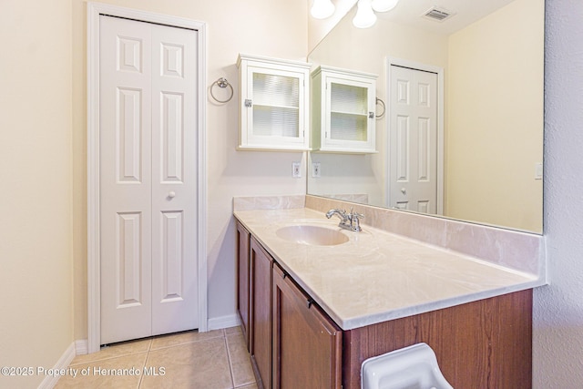 bathroom featuring tile patterned flooring, visible vents, baseboards, a closet, and vanity