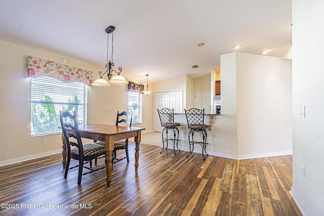 dining space featuring baseboards, lofted ceiling, visible vents, and wood finished floors