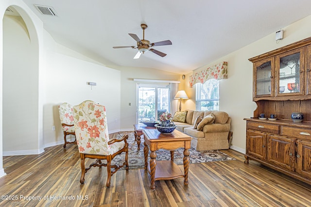 living room featuring visible vents, baseboards, wood finished floors, and vaulted ceiling