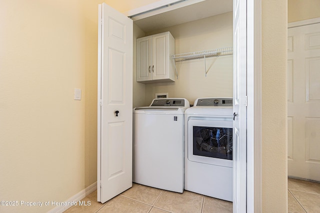 washroom featuring light tile patterned floors, baseboards, cabinet space, and washing machine and dryer