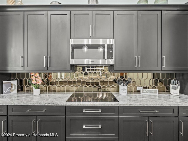 kitchen with black electric stovetop, tasteful backsplash, and gray cabinets